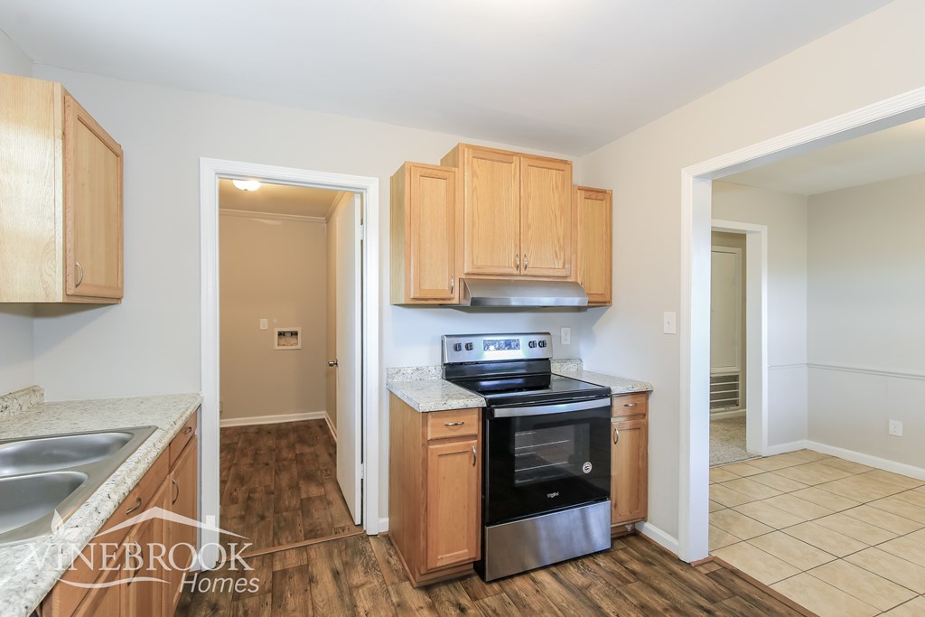 a kitchen with wood flooring and wooden cabinets and black appliances